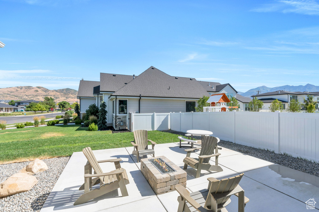 Fenced backyard featuring a fire pit, a mountain view, and a patio