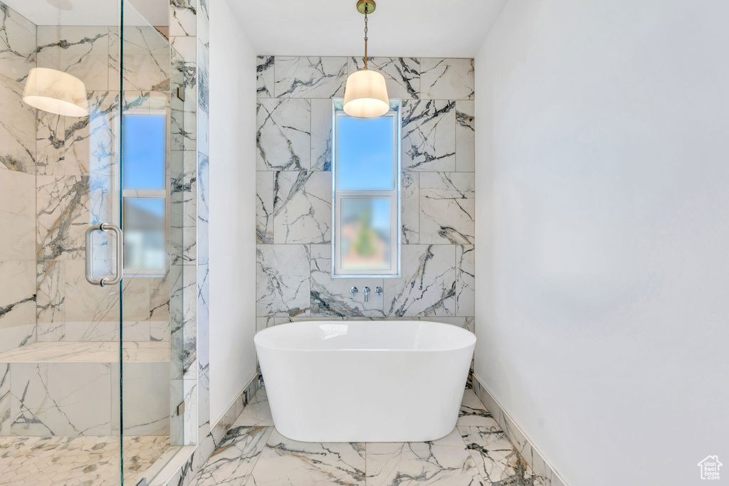 Full bath featuring a soaking tub, a marble finish shower, and marble tiled floors