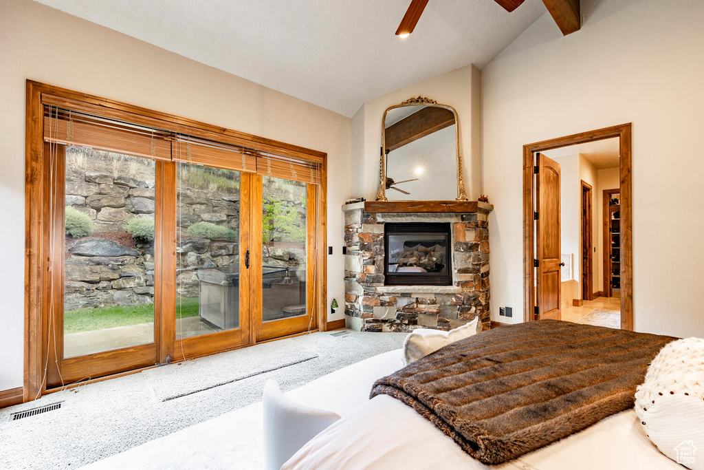 Carpeted bedroom featuring vaulted ceiling, access to exterior, a glass covered fireplace, and ceiling fan