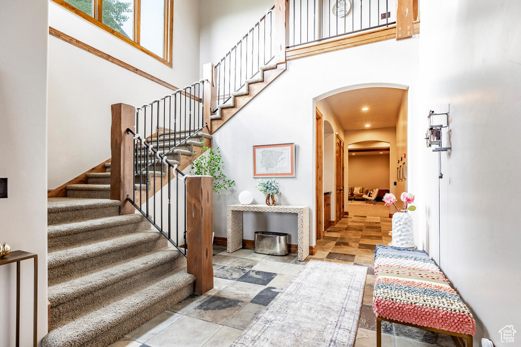 Stairway with arched walkways, a towering ceiling, and stone finish floors