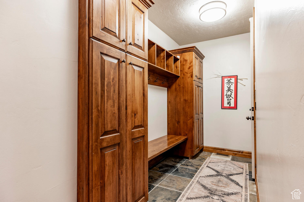 Mudroom with dark stone finish flooring and a textured ceiling