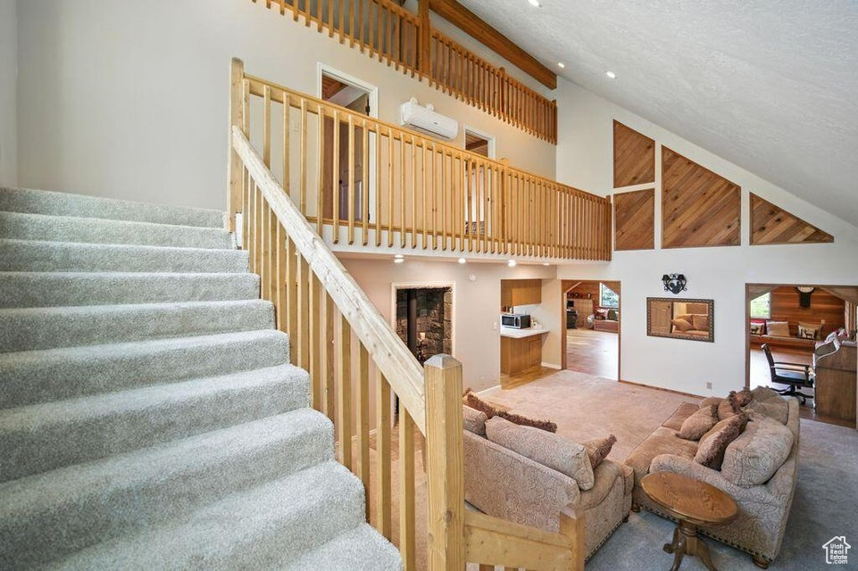 Carpeted living area featuring high vaulted ceiling and stairs