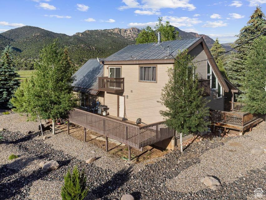 View of side of property with a deck with mountain view, a metal roof, and a balcony