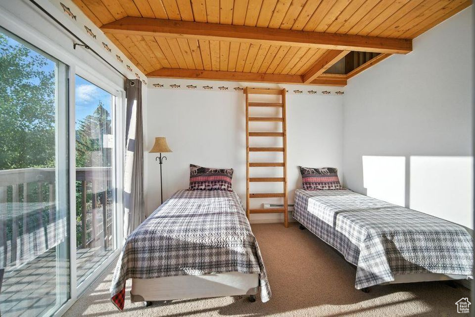 Bedroom with a wood ceiling with exposed beams and carpet floors