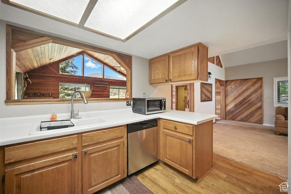 Kitchen with appliances with stainless steel finishes, lofted ceiling, a peninsula, plenty of natural light, and light countertops