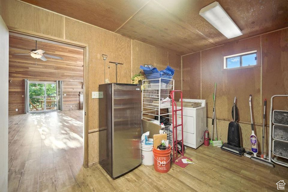 Kitchen with washer / dryer, freestanding refrigerator, wood finished floors, healthy amount of natural light, and wooden walls