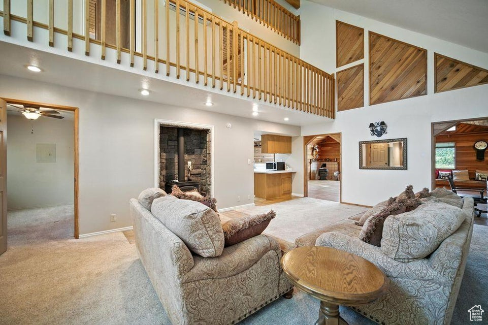 Living area featuring high vaulted ceiling, light carpet, and a ceiling fan