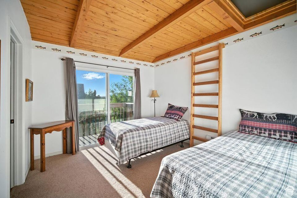 Bedroom with a wood ceiling with exposed beams, carpet, and access to outside