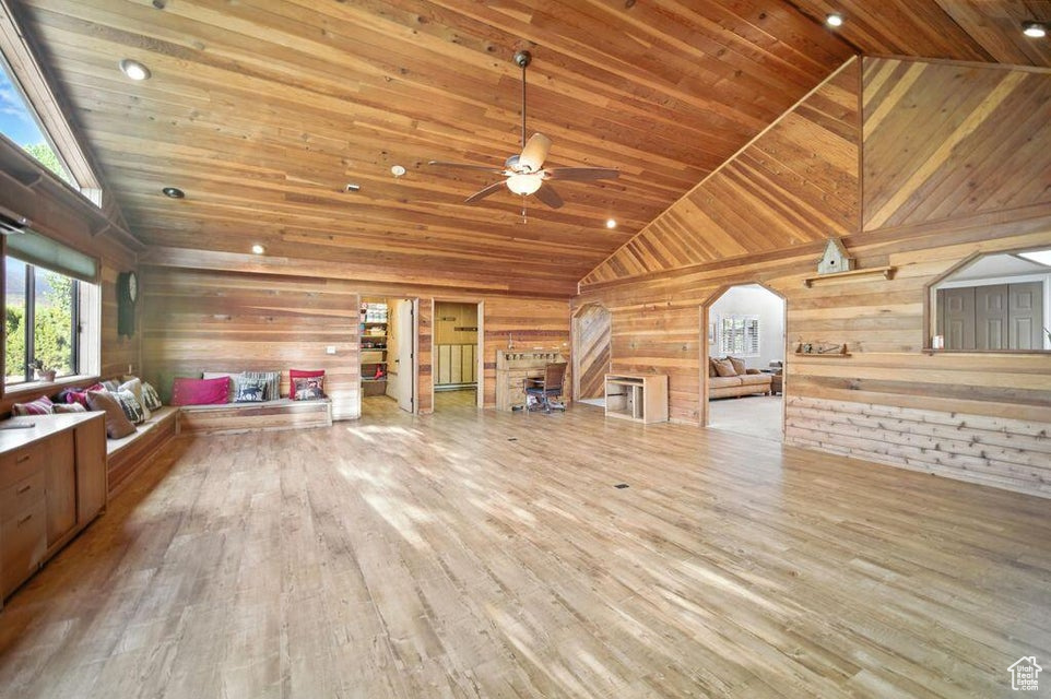 Bonus room featuring wooden walls, wood finished floors, high vaulted ceiling, a ceiling fan, and wood ceiling