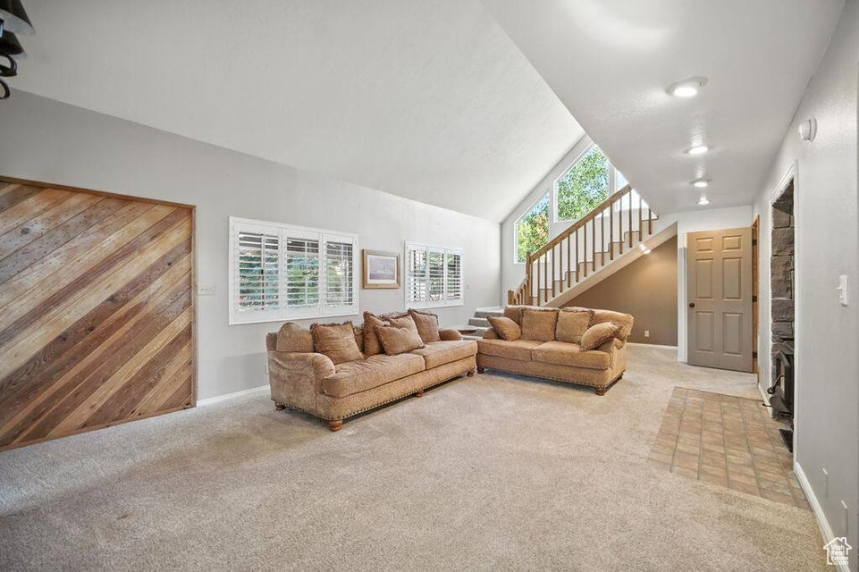 Living area featuring carpet, stairs, and lofted ceiling