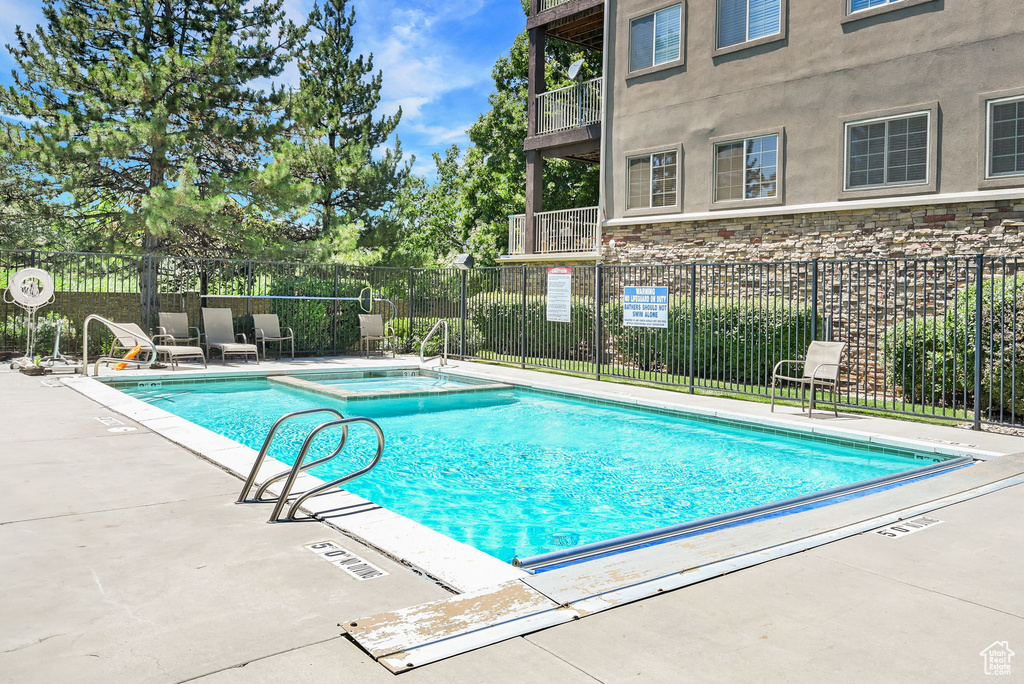 View of pool with a patio and a pool with connected hot tub