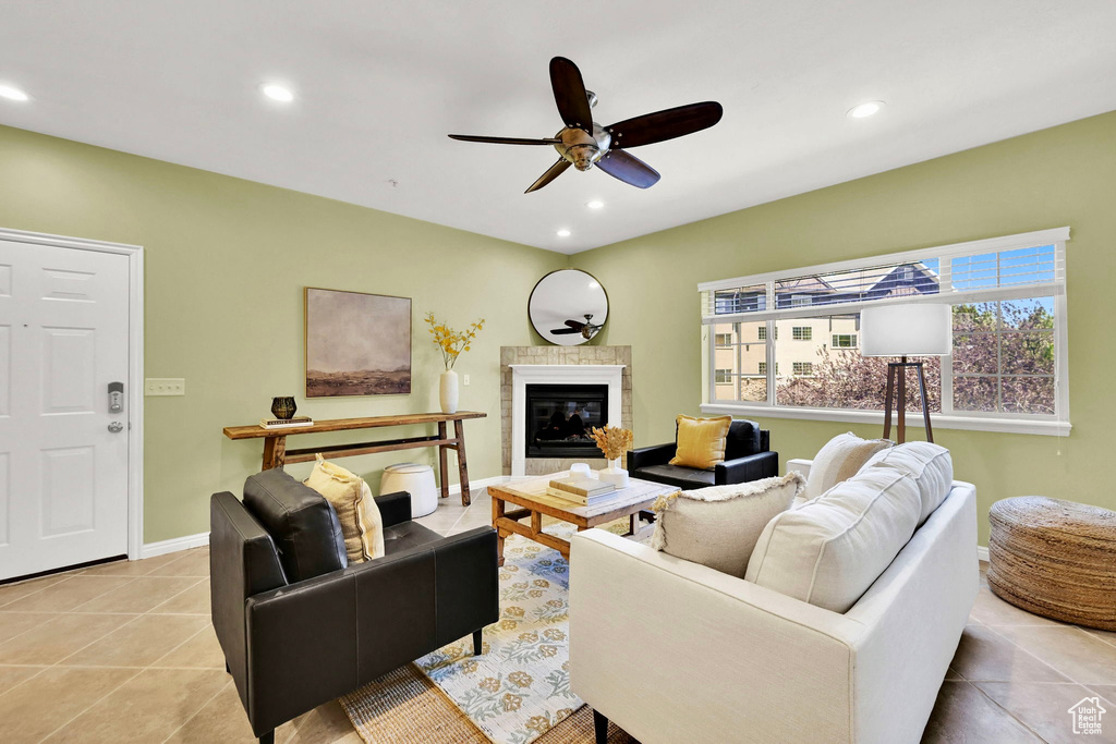 Living area featuring a ceiling fan, recessed lighting, light tile patterned floors, and a glass covered fireplace