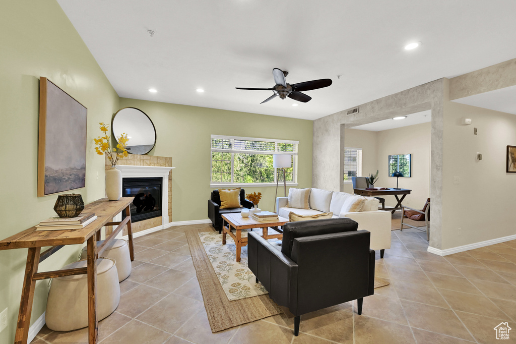 Living room with light tile patterned flooring, recessed lighting, a glass covered fireplace, and ceiling fan