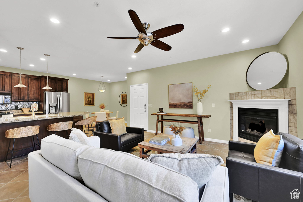 Living room with light tile patterned floors, ceiling fan, recessed lighting, and a glass covered fireplace