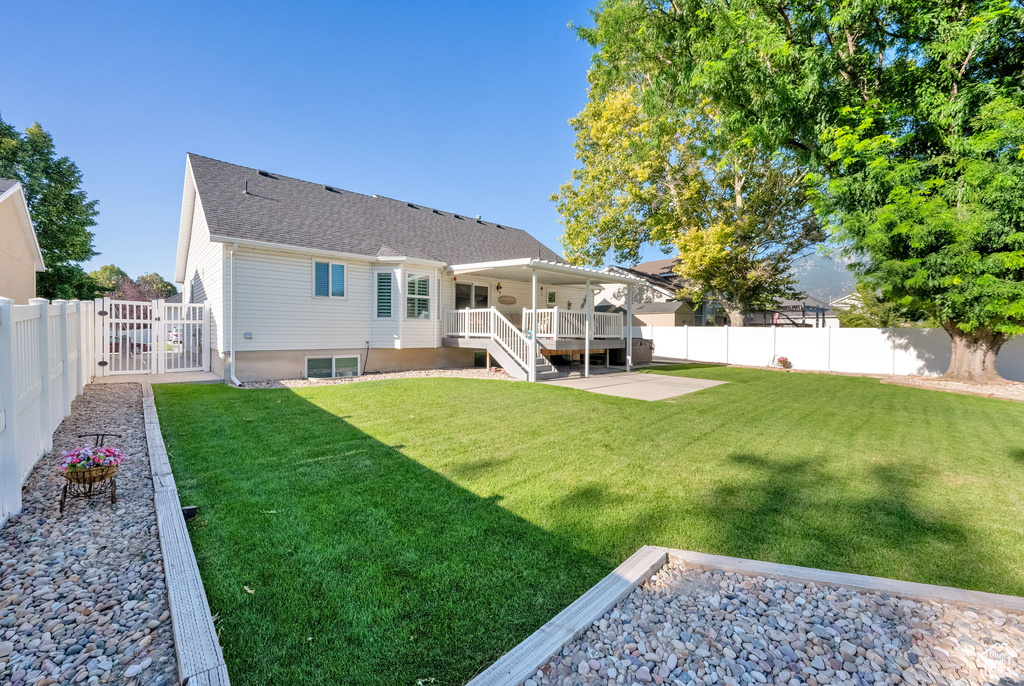 Back of property with a fenced backyard, a patio area, a gate, a wooden deck, and a shingled roof