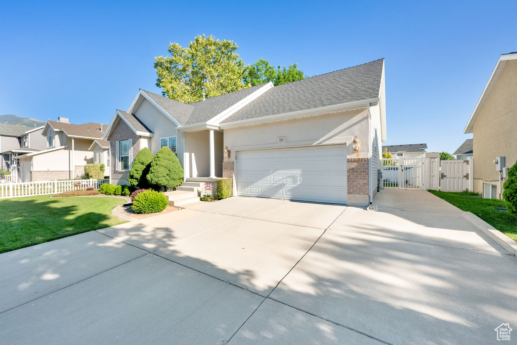 Ranch-style house with a gate, a residential view, driveway, an attached garage, and brick siding
