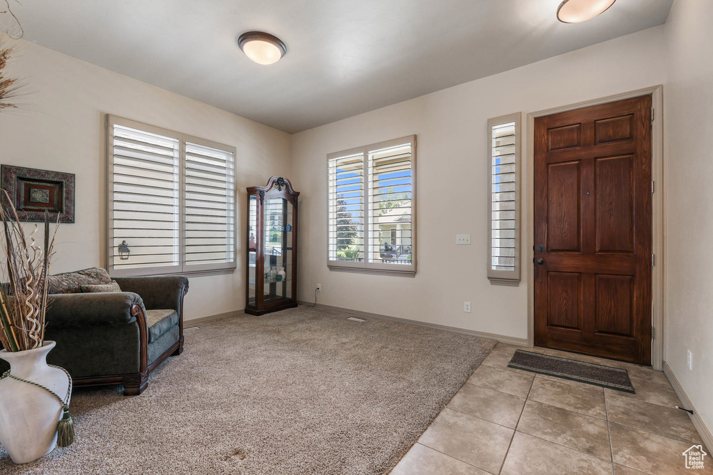 Foyer entrance with light tile patterned flooring and light colored carpet