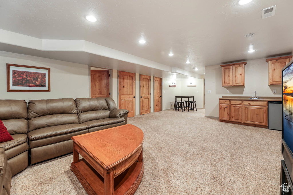 Living room with recessed lighting, wet bar, and light carpet