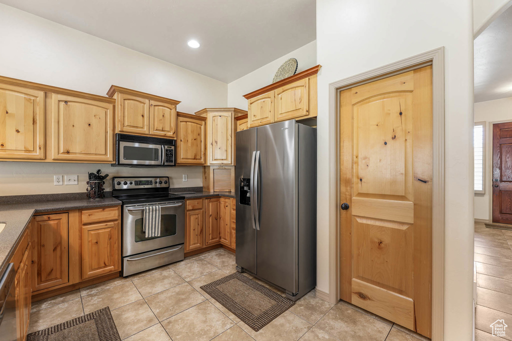 Kitchen with appliances with stainless steel finishes, dark countertops, light tile patterned floors, and recessed lighting