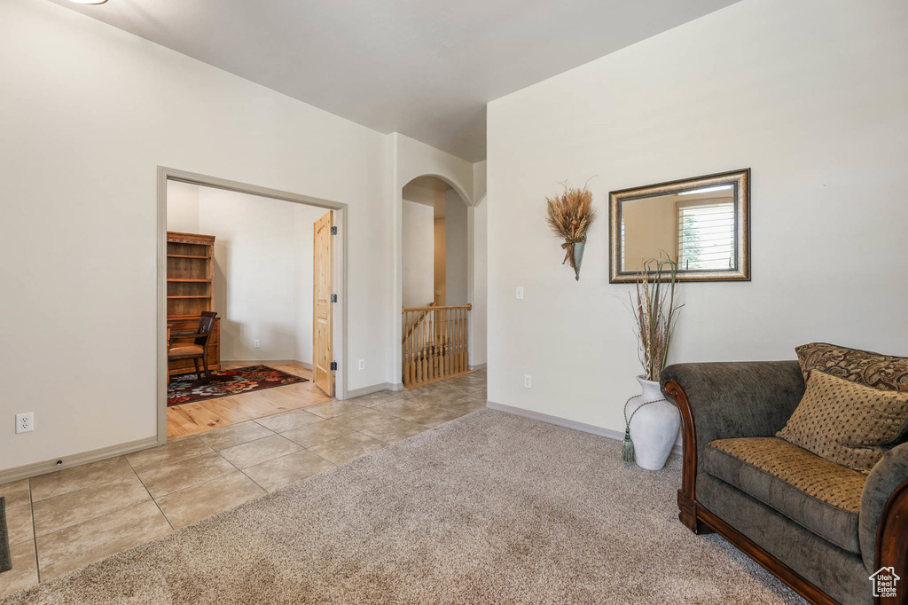 Living area with light tile patterned flooring, light carpet, and arched walkways