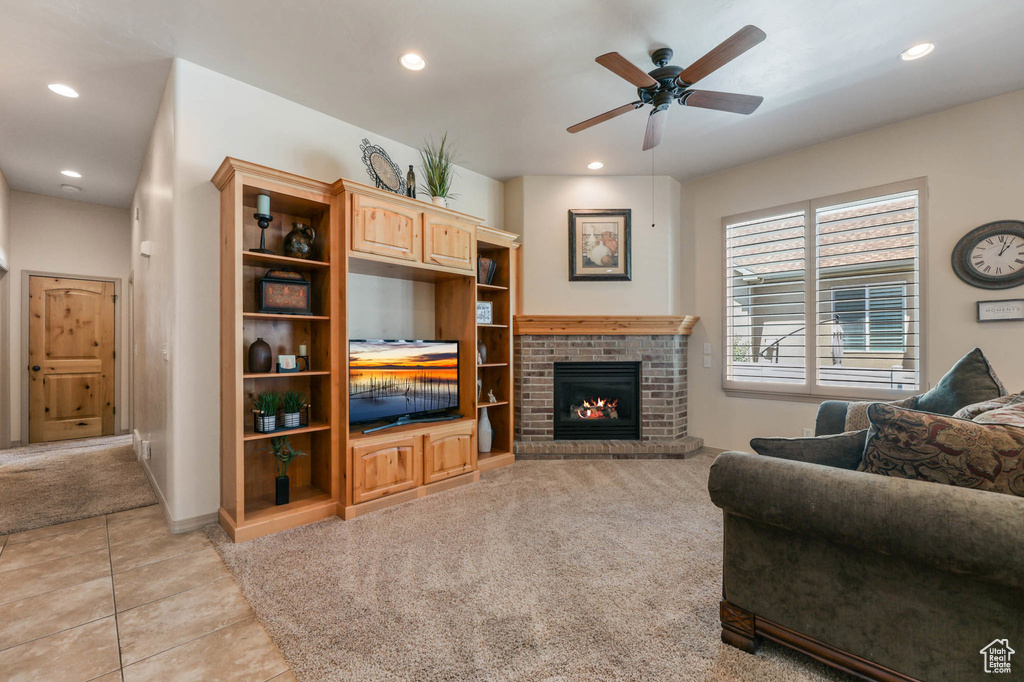 Living room with a ceiling fan, recessed lighting, a fireplace, light tile patterned floors, and light carpet