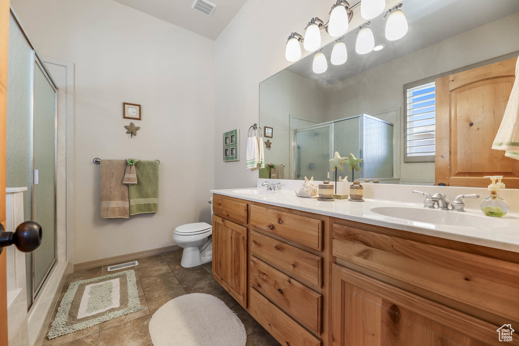 Full bathroom with a stall shower, double vanity, tile patterned floors, and lofted ceiling