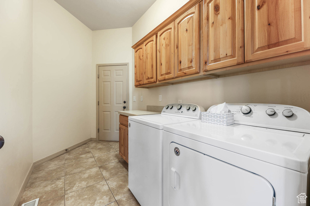 Washroom featuring cabinet space, separate washer and dryer, and light tile patterned floors