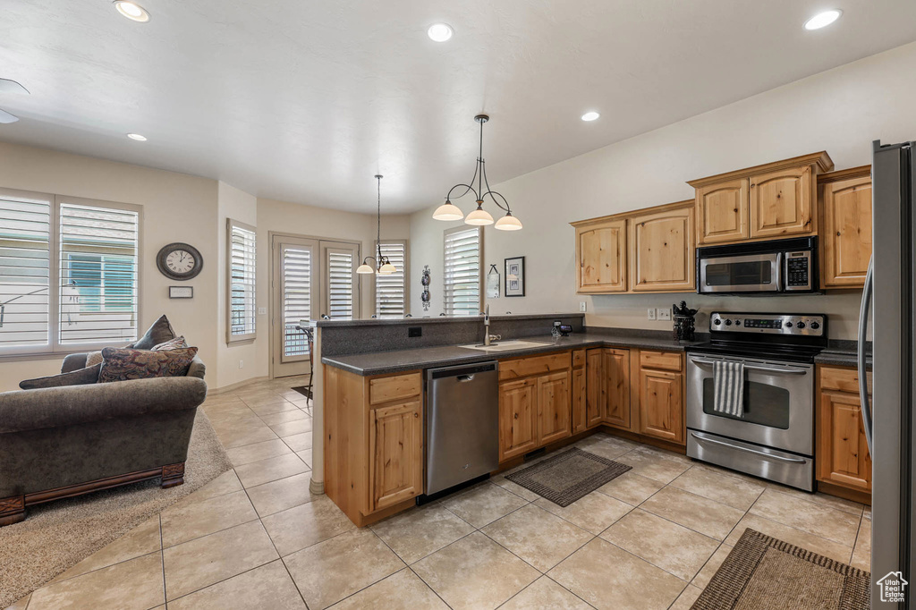 Kitchen with appliances with stainless steel finishes, dark countertops, open floor plan, a peninsula, and recessed lighting