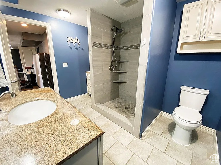 Bathroom featuring vanity, a tile shower, and tile patterned flooring