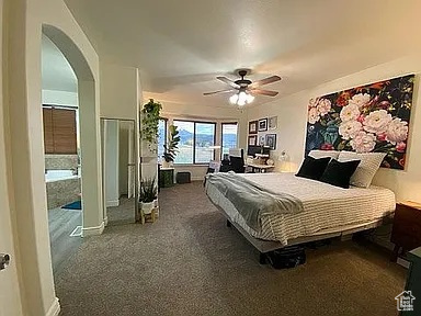 Bedroom with arched walkways, carpet floors, and ceiling fan