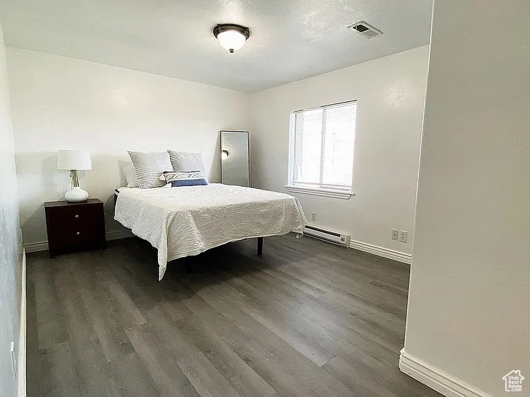 Bedroom featuring a baseboard radiator and dark wood finished floors
