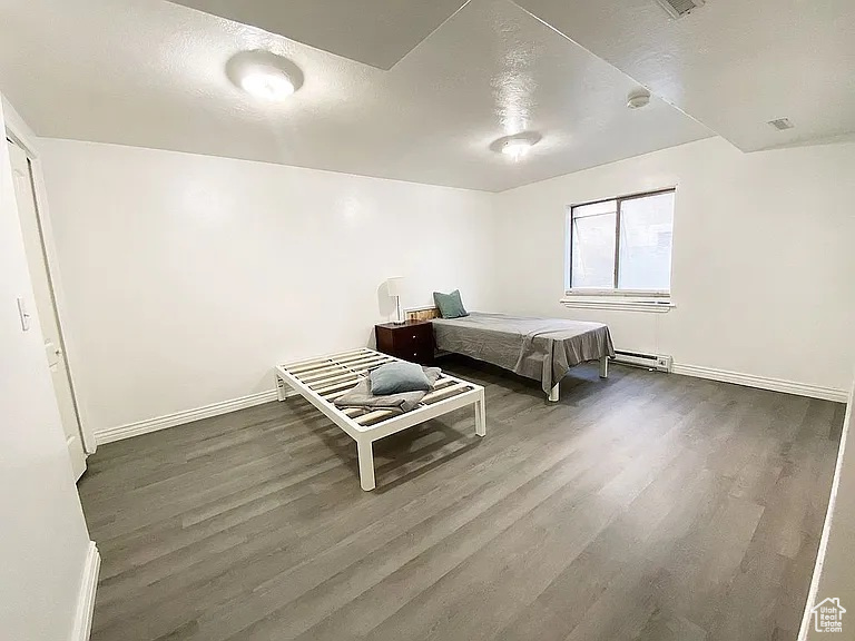 Bedroom with wood finished floors and a baseboard radiator