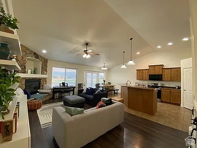 Living room with a ceiling fan, a fireplace, lofted ceiling, recessed lighting, and dark wood-style flooring