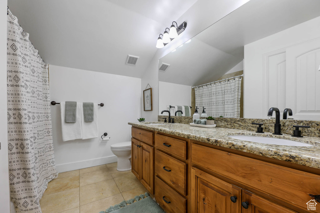 Bathroom featuring double vanity, vaulted ceiling, tile patterned flooring, and a shower with shower curtain