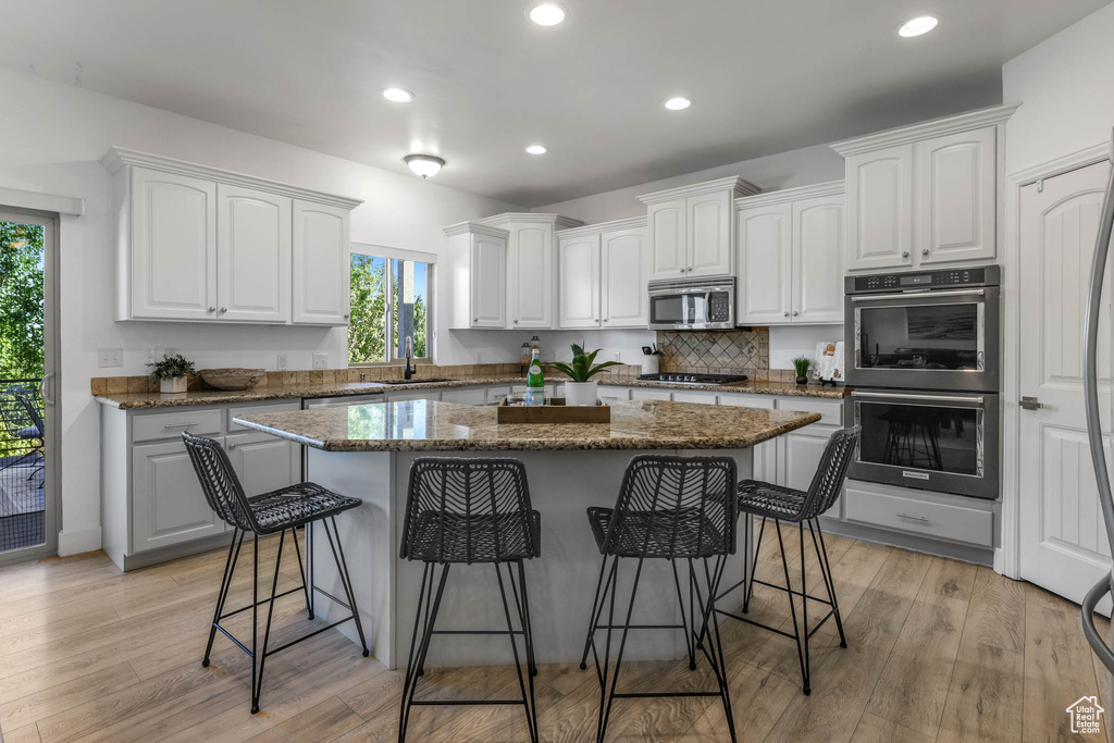 Kitchen with appliances with stainless steel finishes, healthy amount of natural light, a kitchen island, a breakfast bar area, and recessed lighting