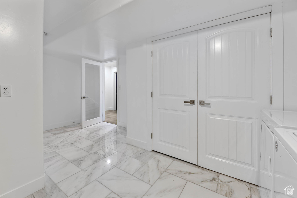 Basement featuring washing machine and clothes dryer and light marble finish floors