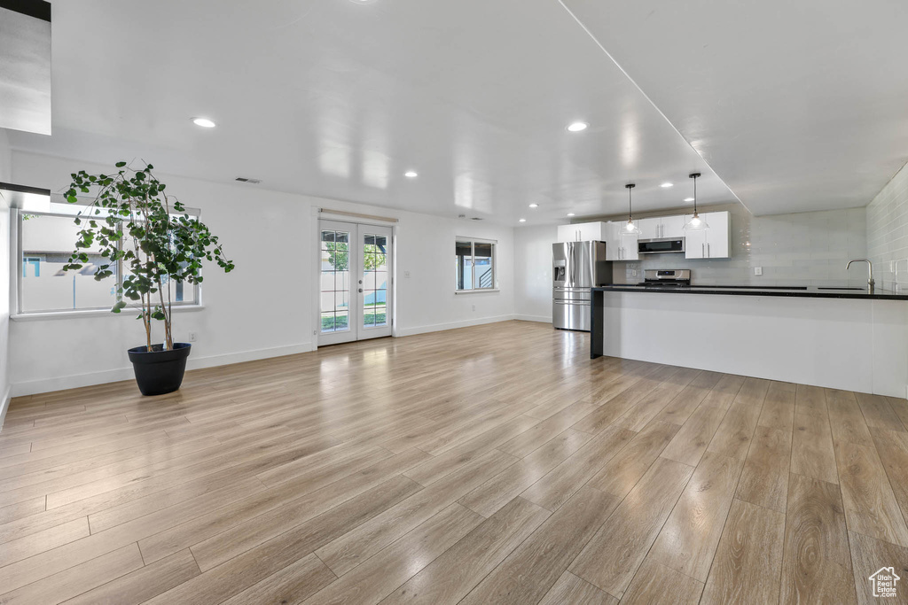 Unfurnished living room with light wood-type flooring, recessed lighting, and french doors