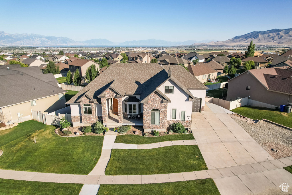 French country home featuring concrete driveway, stone siding, a residential view, and a mountain view