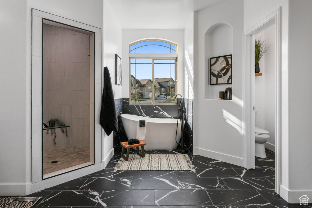 Full bath featuring marble finish floors, a soaking tub, and a shower stall