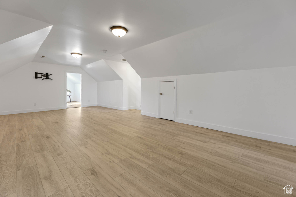 Additional living space featuring light wood finished floors and vaulted ceiling
