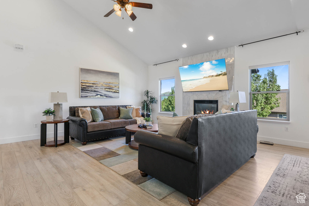 Living room featuring a fireplace, recessed lighting, ceiling fan, light wood-style floors, and plenty of natural light