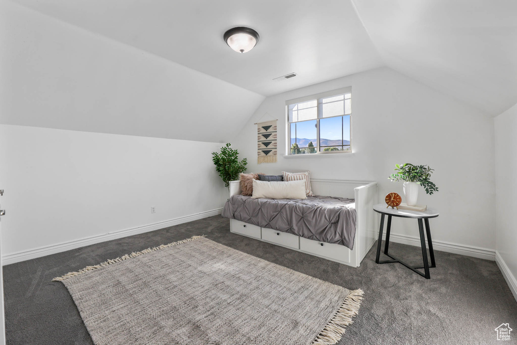 Carpeted bedroom with lofted ceiling and baseboards