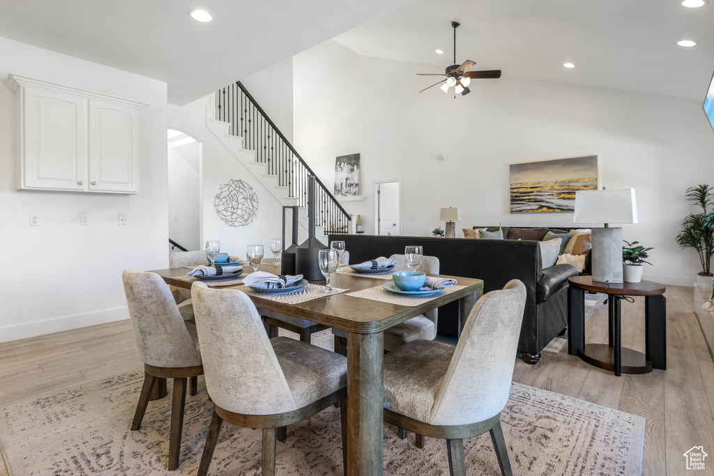Dining space featuring stairway, a ceiling fan, light wood-style flooring, recessed lighting, and high vaulted ceiling