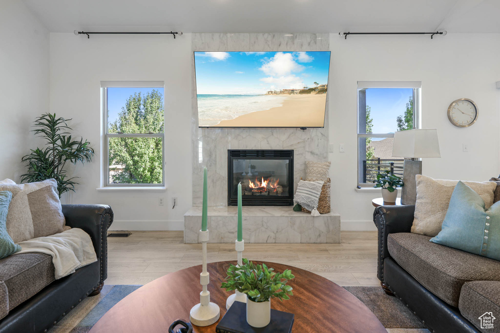 Living room with track lighting, a glass covered fireplace, wood finished floors, and plenty of natural light