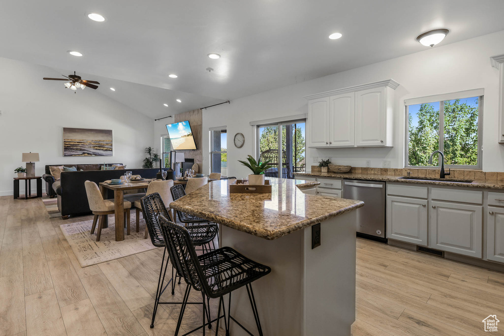 Kitchen featuring dishwasher, a breakfast bar area, light wood-style flooring, a ceiling fan, and recessed lighting