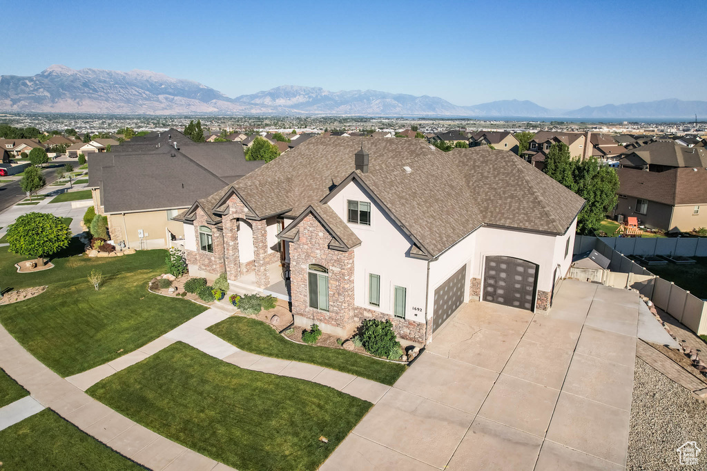 View of front of house with a garage, stucco siding, roof with shingles, concrete driveway, and a residential view