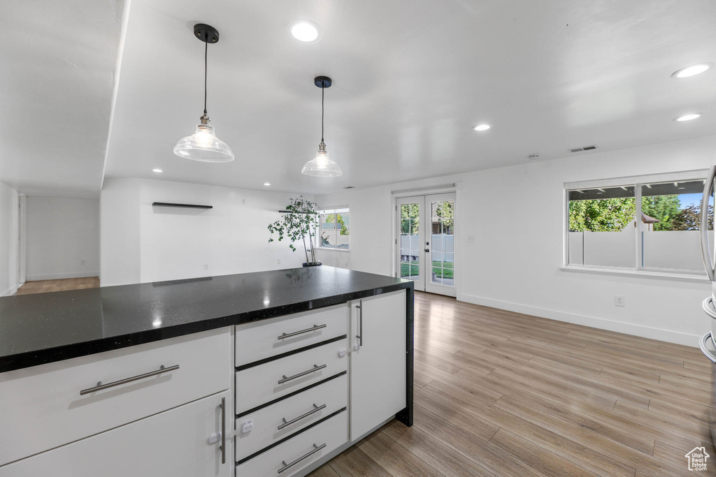 Kitchen with recessed lighting, french doors, white cabinetry, light wood-style floors, and dark countertops