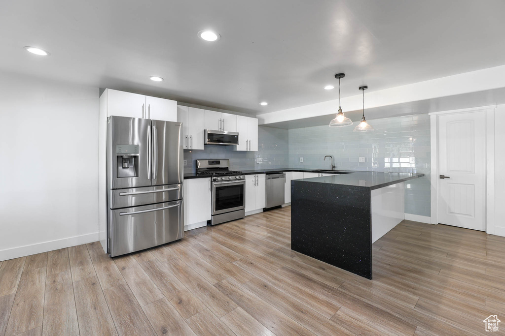Kitchen featuring appliances with stainless steel finishes, dark countertops, a peninsula, white cabinets, and recessed lighting