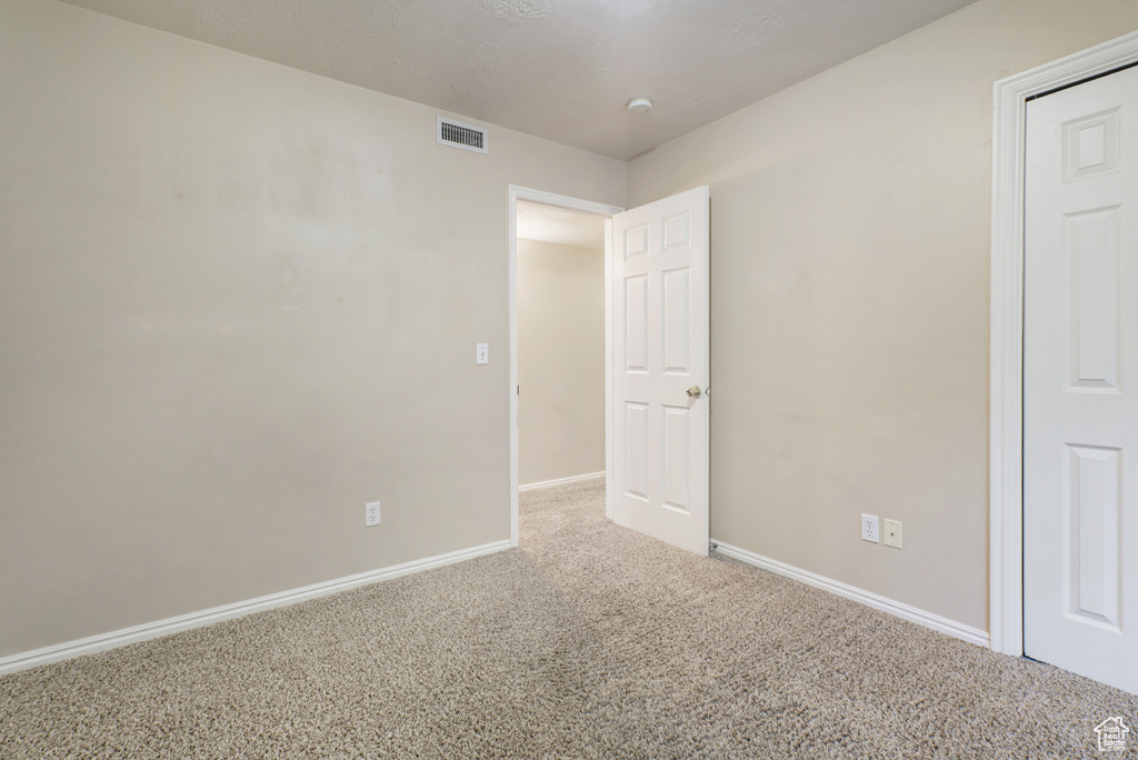 Empty room with carpet and a smoke detector