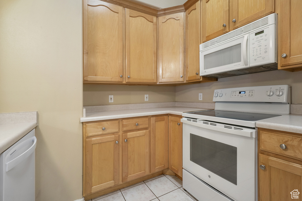 Kitchen with white appliances, light tile patterned flooring, and light countertops